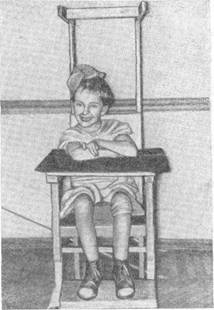 Сидение на приспособленном стуле с прибитыми ручками, подставкой для ног с накладным столиком