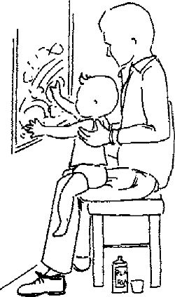 Ребенок сидит верхом на папином колене и рисует на зеркале краской из пульверизатора
